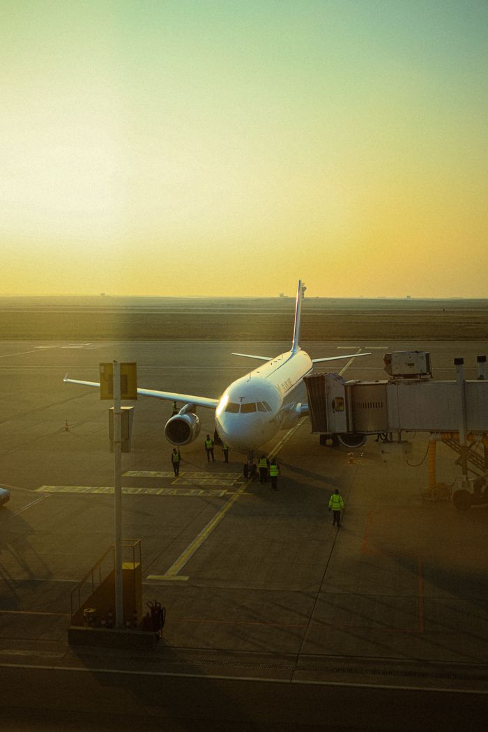 Home A commercial airplane parked at Erbil Airport during a warm sunset, preparing for boarding.